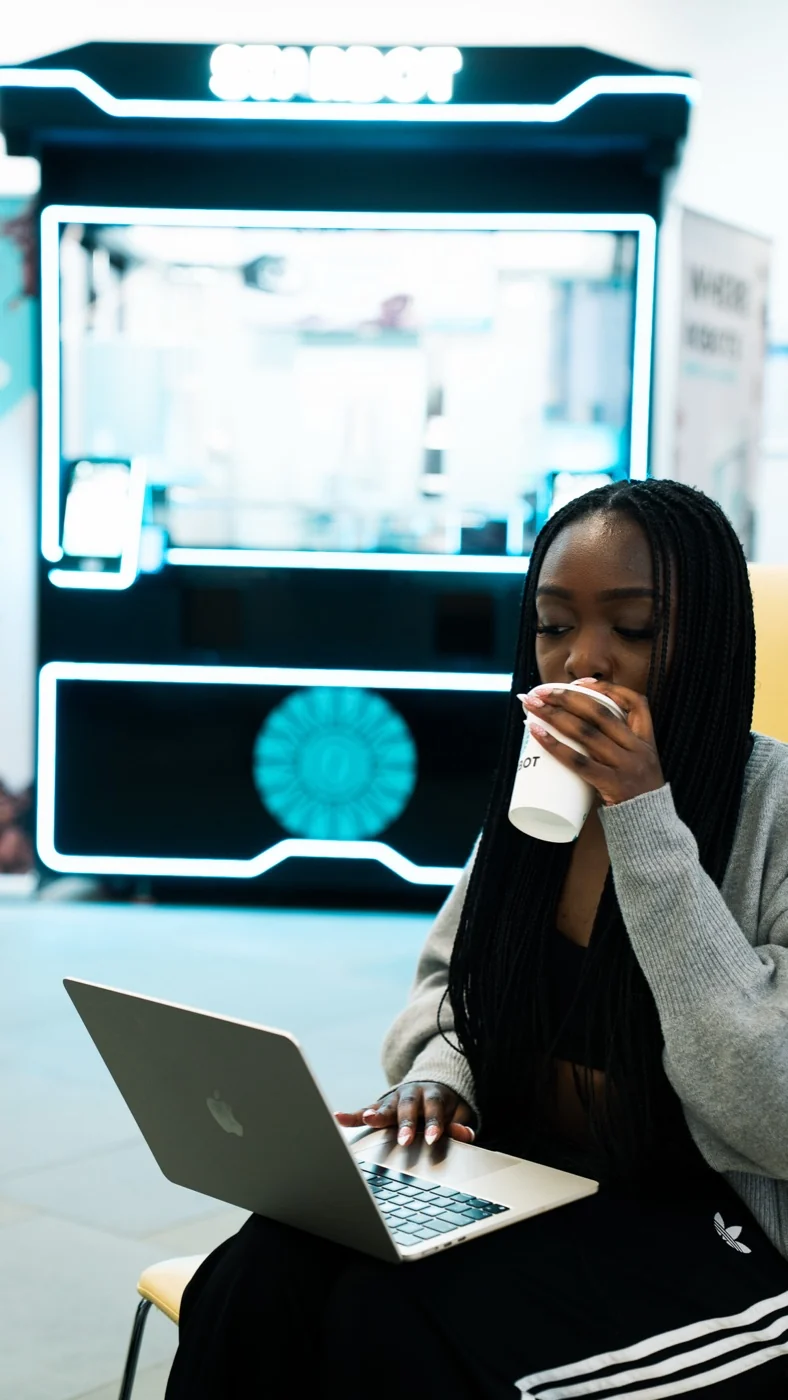 A student working on a laptop beside the kiosk with a Starbot cup