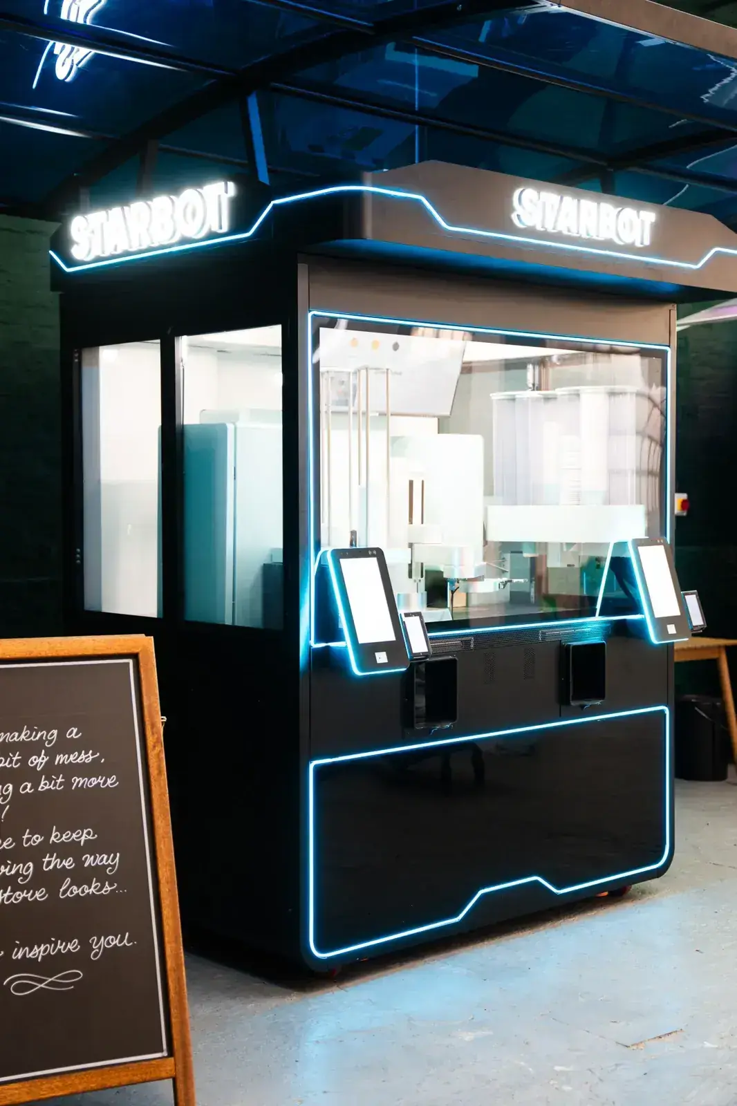 The STARBOT kiosk from the side, showing its footprint against a wall