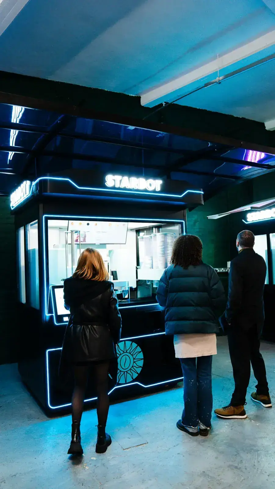 Three customers ordering at the STARBOT coffee kiosk in London