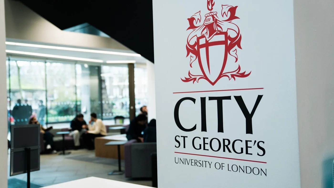 The university entrance sign beside the kiosk's pitch